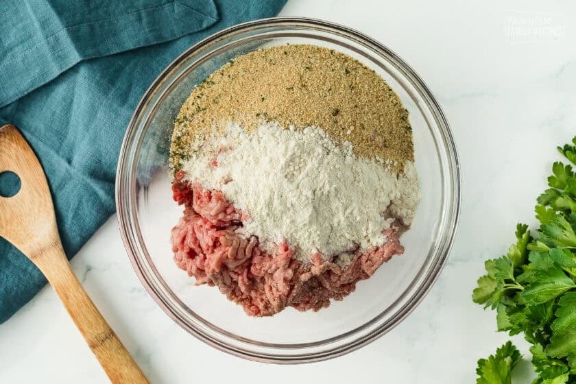 Meatloaf dry ingredients in a bowl including ground meats, flour, and breadcrumbs.