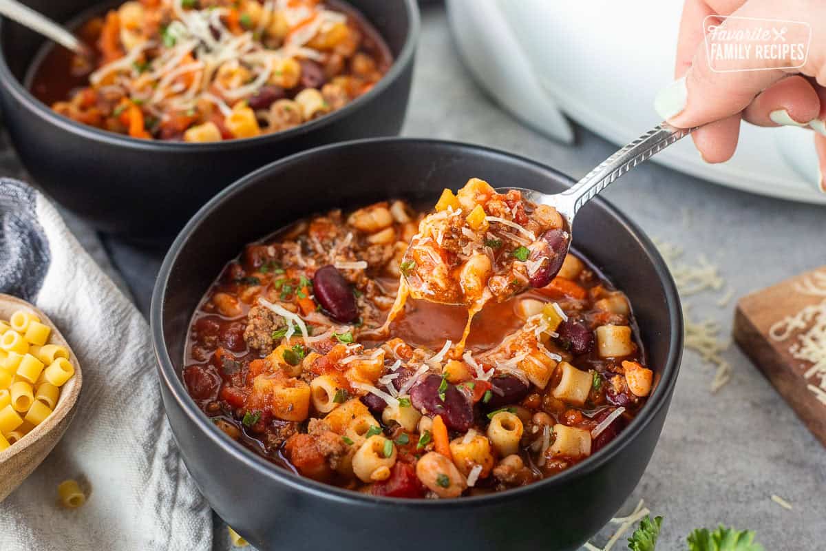 Lifting a spoon full of Pasta e Fagioli out of a bowl.