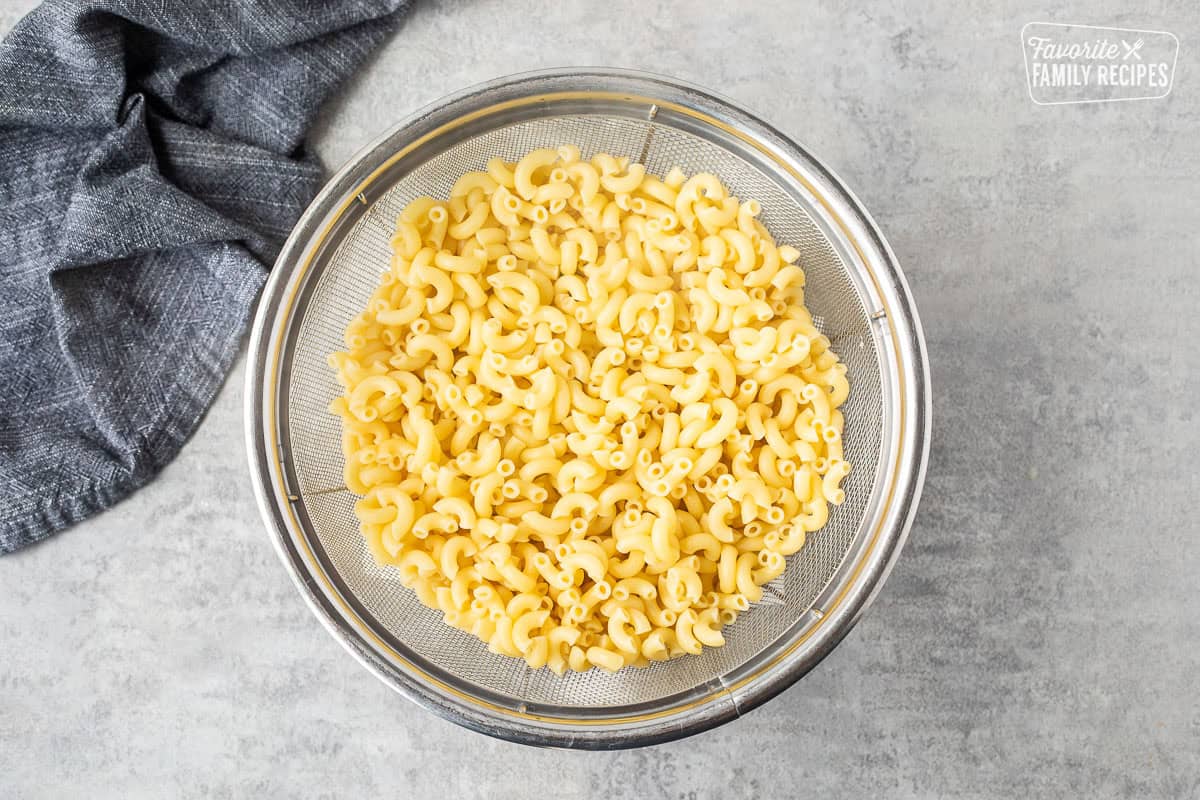 Cooked macaroni in a strainer without any seasoning, ready to mix with cheese to make mac and cheese with pulled pork