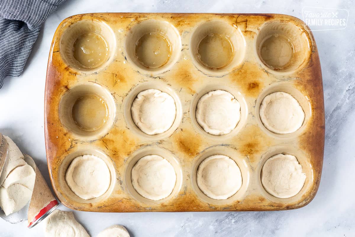 Pressing refrigerated biscuit into muffin pan.