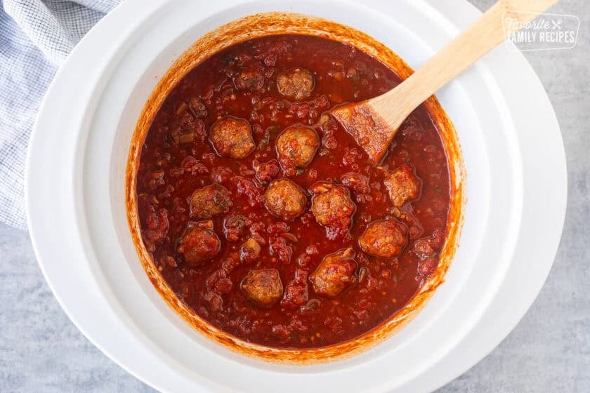 Stirring meatballs into crockpot spaghetti sauce.