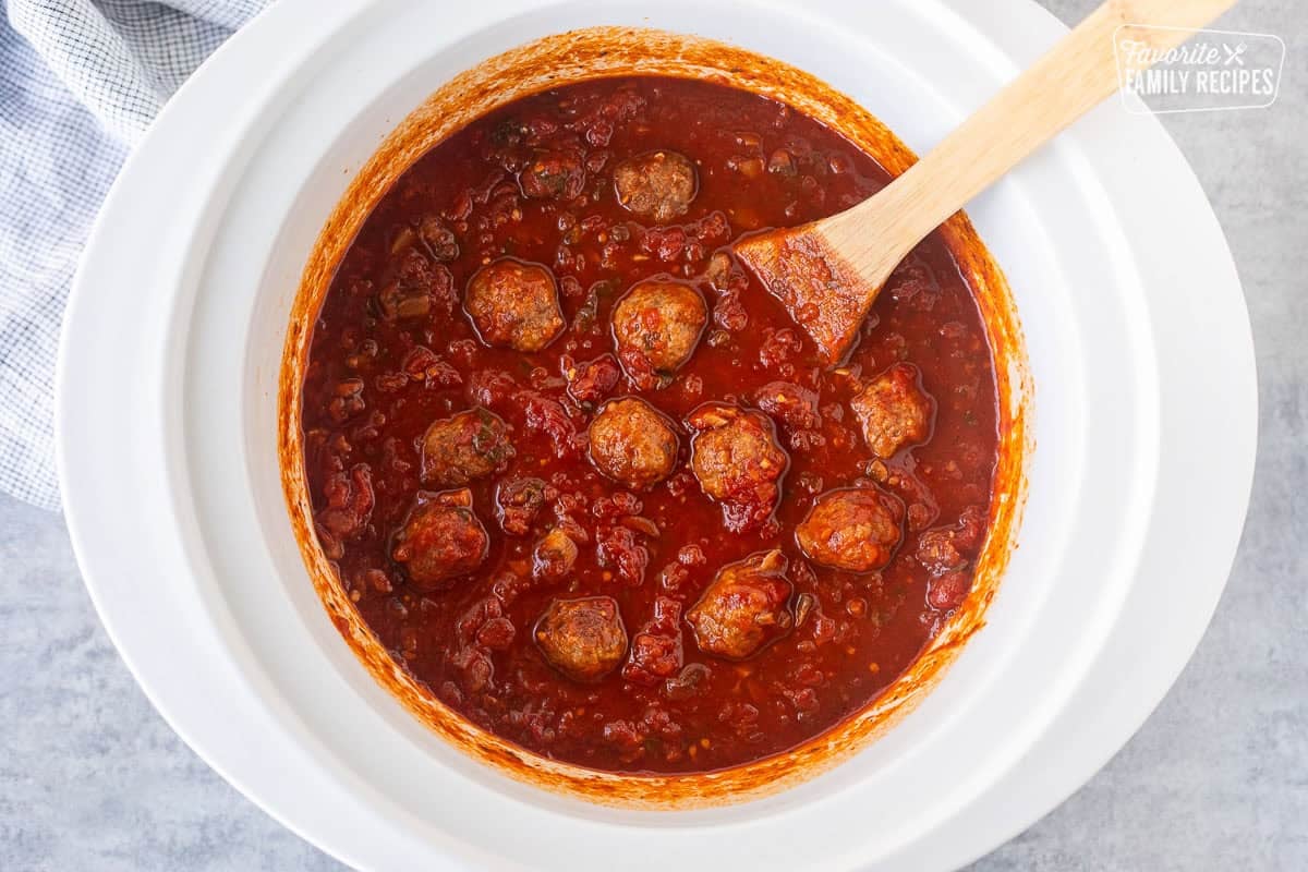 Stirring meatballs into crockpot spaghetti sauce.