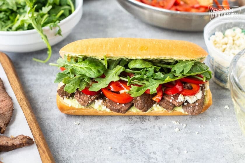 Steak Sandwich on a French roll with pesto mayo, red pepper, blue cheese crumbles, arugula and spinach mix.