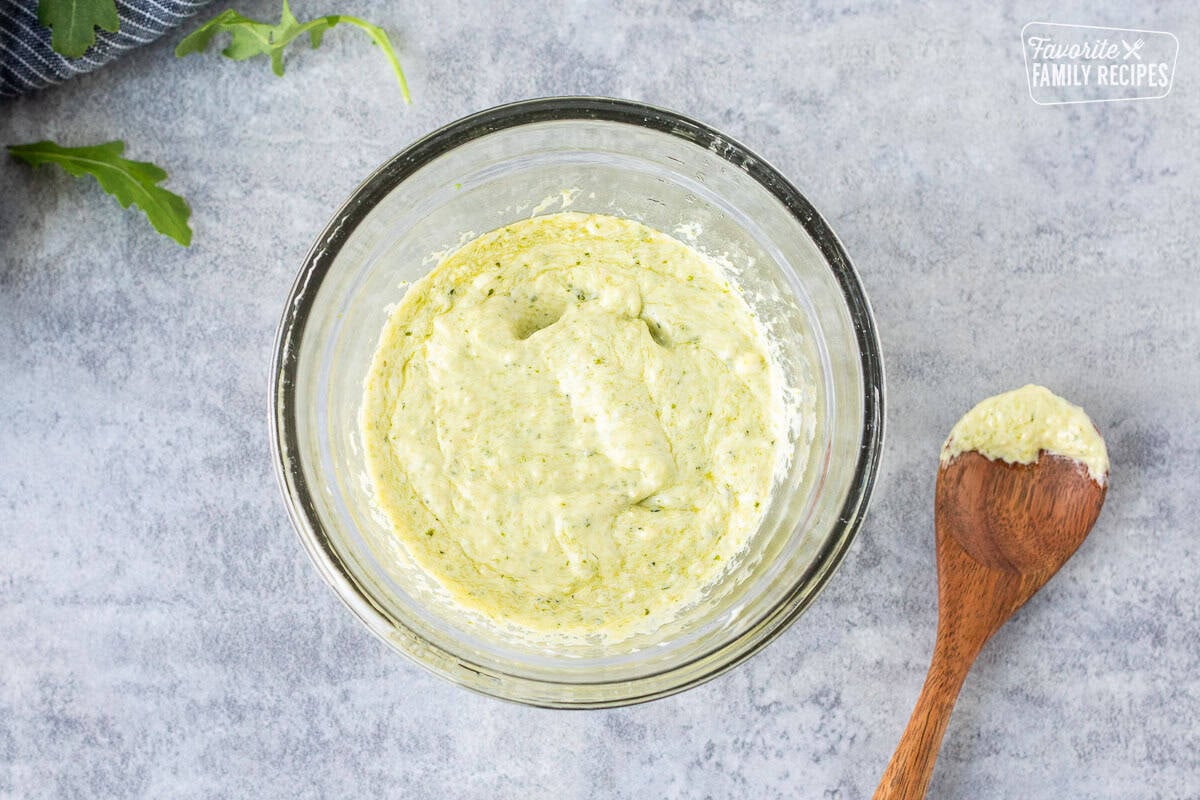 Bowl with pesto mayo and a spoon.