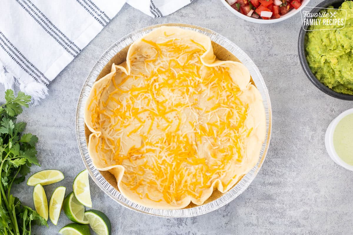 Metal dish with a large flour tortilla and melted Mexican shredded cheese on top.