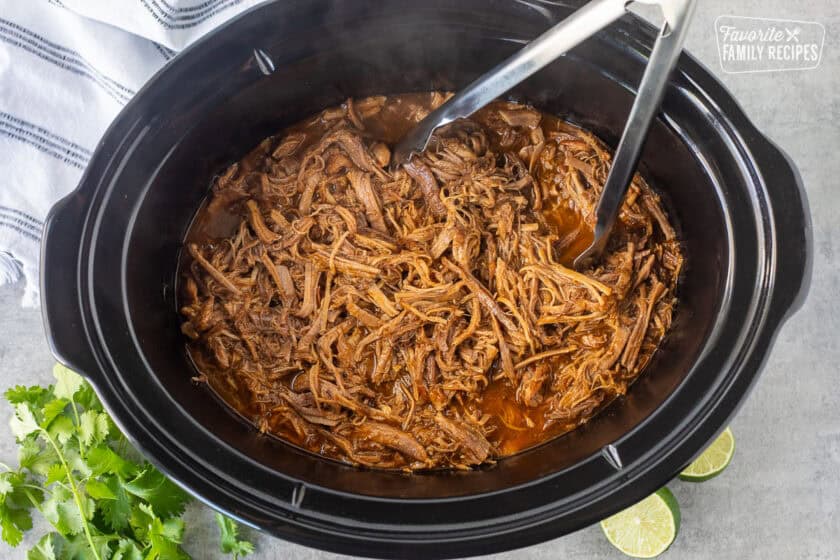 Crockpot with cooked Cafe Rio sweet pork and tongs.