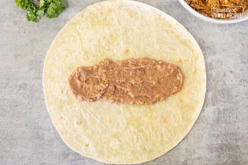 Refried beans spread on a flour tortilla.