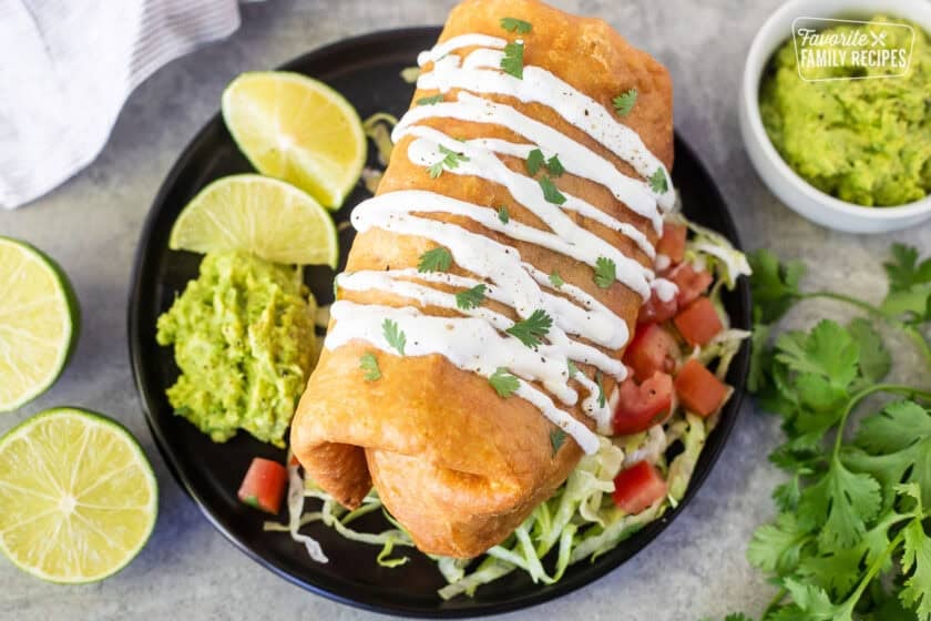 Chicken Chimichanga on a plate with sour cream drizzled on top and cilantro.