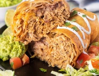 Chicken Chimichanga cut open with sour cream drizzled on top and cilantro.