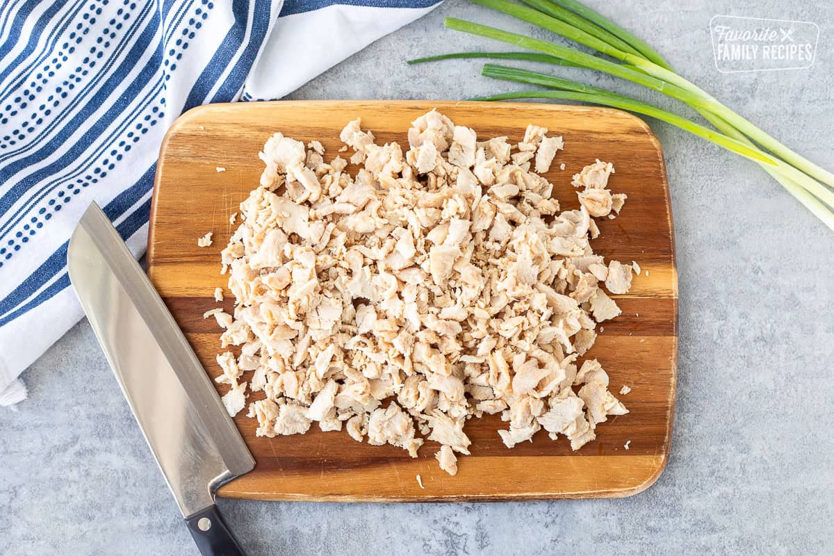 Cutting board with velvet chicken chopped with knife.