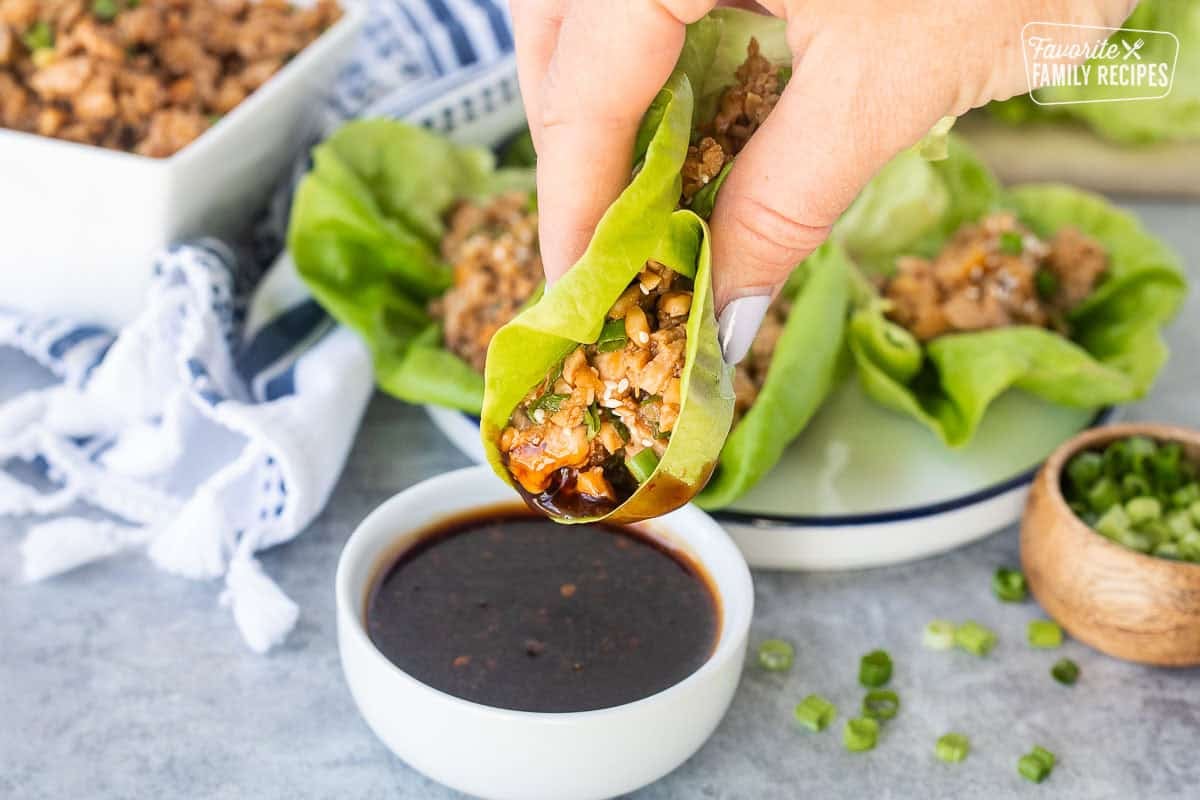 Dipping a chicken lettuce wrap into sauce.