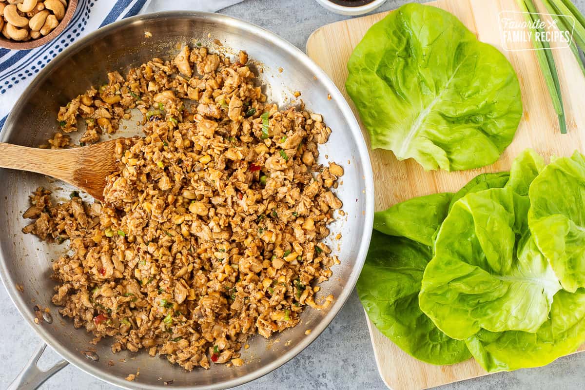 Skillet with lettuce wrap chicken and washed butter lettuce leaves.