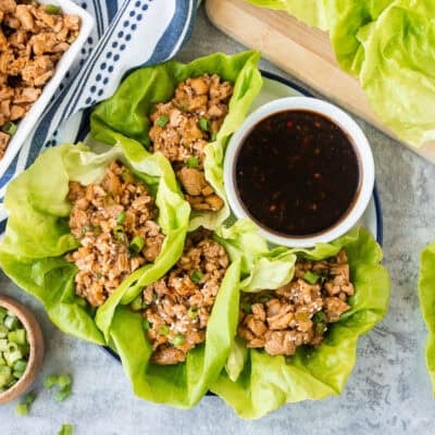 PF Changs-style Chicken lettuce wraps on a plate with small bowl of dipping sauce on the side.