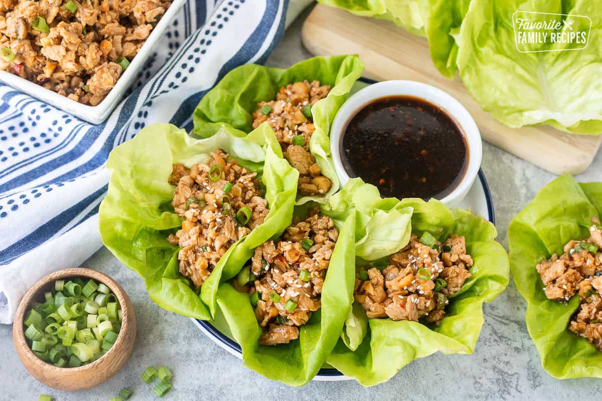 PF Changs-style Chicken lettuce wraps on a plate with small bowl of dipping sauce on the side.
