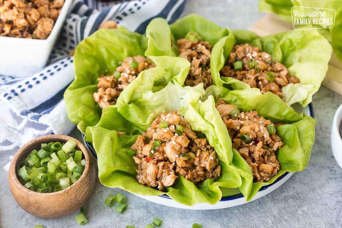 Five chicken lettuce wraps like P.F. Chang's on a plate with sauce on the side.