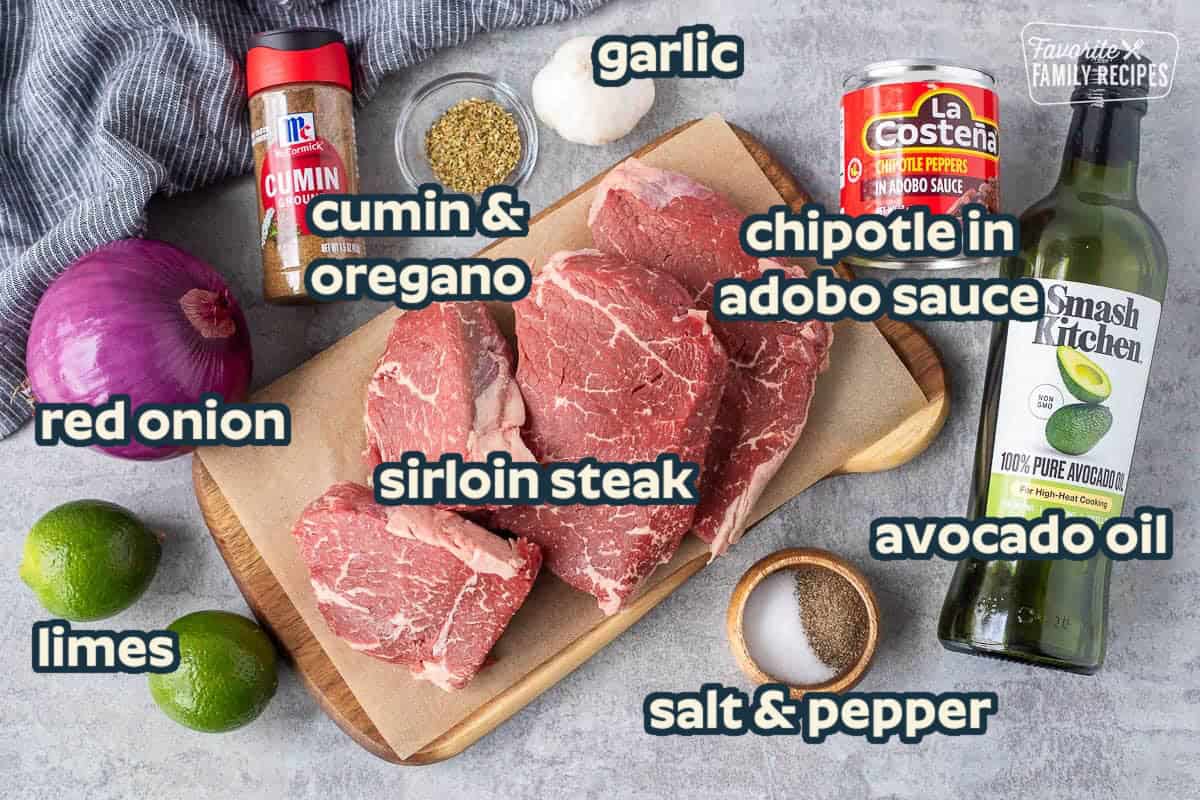 Ingredients to make Chipotle steak including top sirloin steaks, avocado oil, chipotle peppers in adobo sauce, salt, pepper, oregano, garlic, cumin, red onion and lime juice.