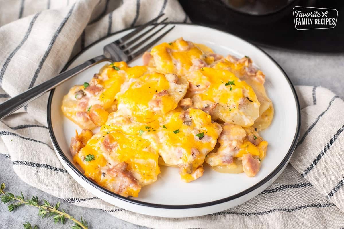 Crockpot ham and scalloped potatoes on a plate with a fork.