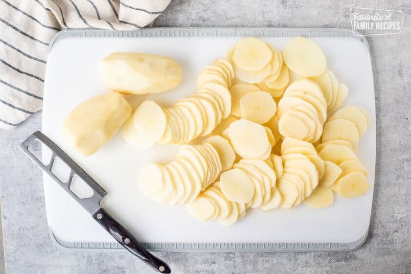 Cutting board with peeled and sliced potatoes.