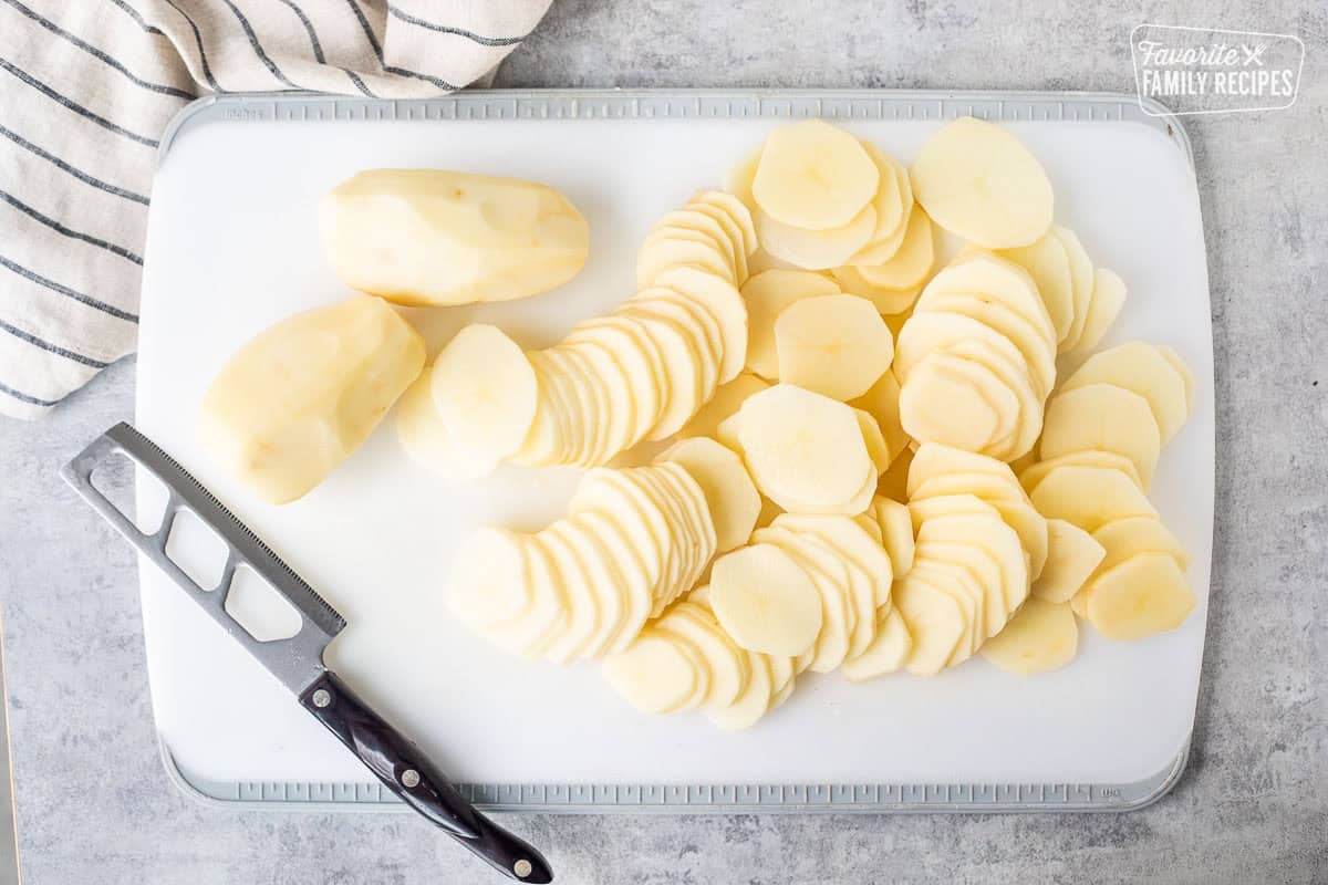 Cutting board with peeled and sliced potatoes.