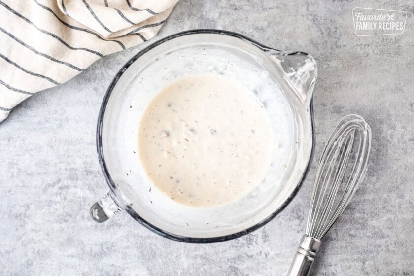 Cream of mushroom soup mixture in glass bowl and whisk on the side.
