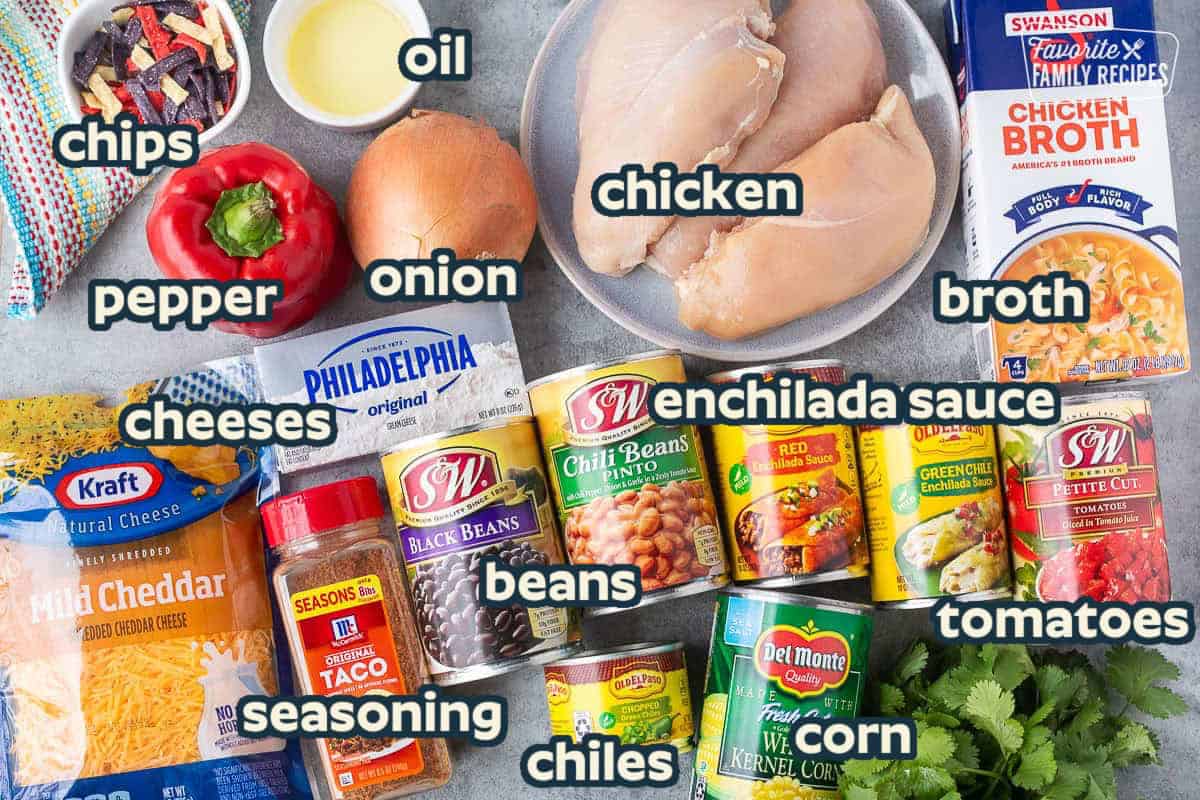 Ingredients to make Instant Pot Chicken Enchilada Soup including chicken, chicken broth, diced tomatoes, green enchilada sauce, red enchilada sauce, chili beans, canned corn, green chilies, black beans, taco seasoning, cheddar cheese, cream cheese, onion, red pepper, oil and tortilla strips.