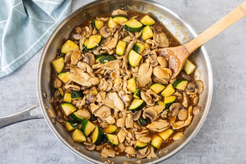 Skillet with sauce added to chicken, mushroom, and zucchini mixture.