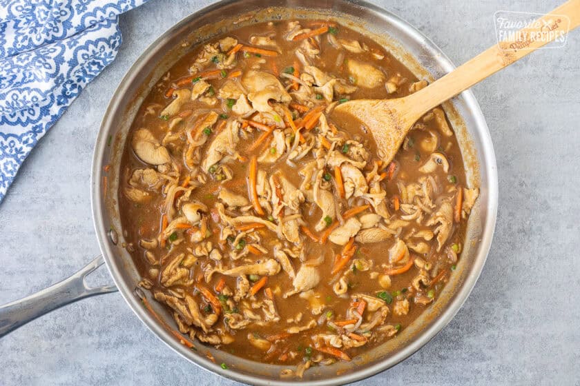 Peanut noodles sauce in the skillet and wooden spoon.
