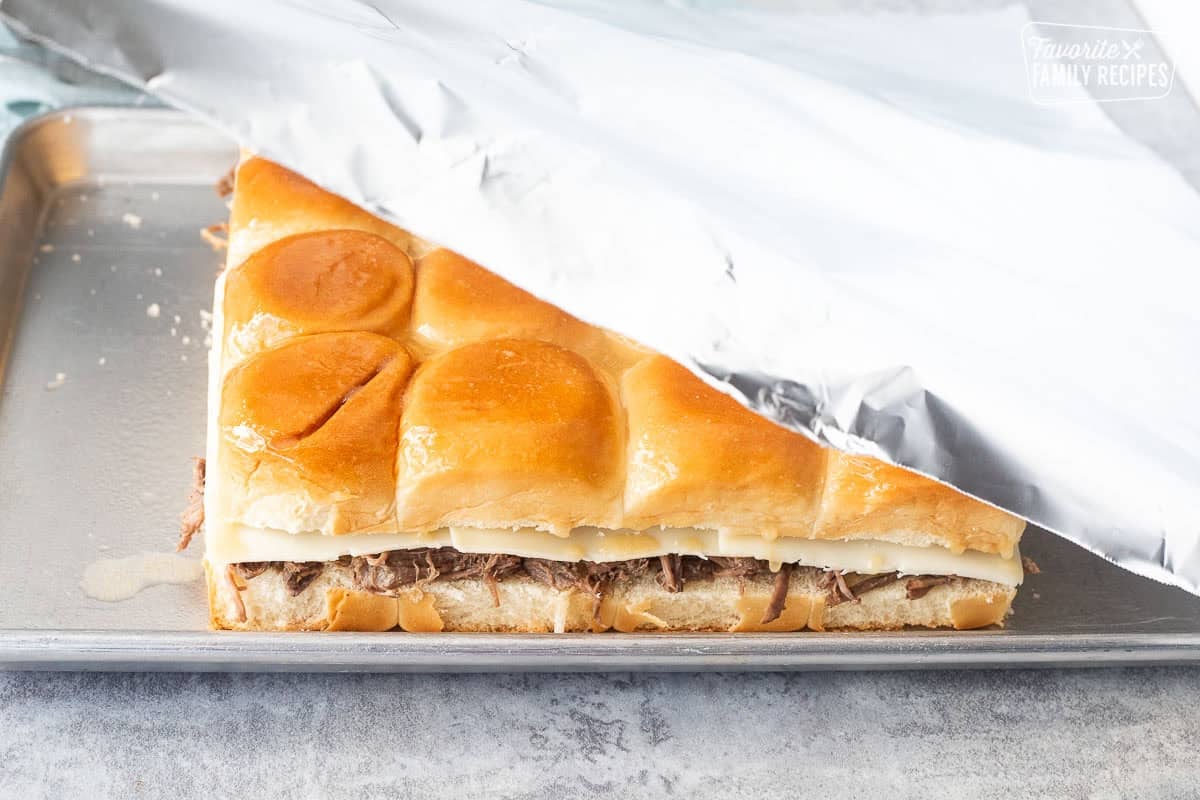 Covering roast beef sliders with foil.