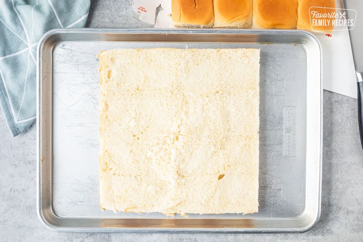 Hawaiian rolls cut in half on sheet pan.