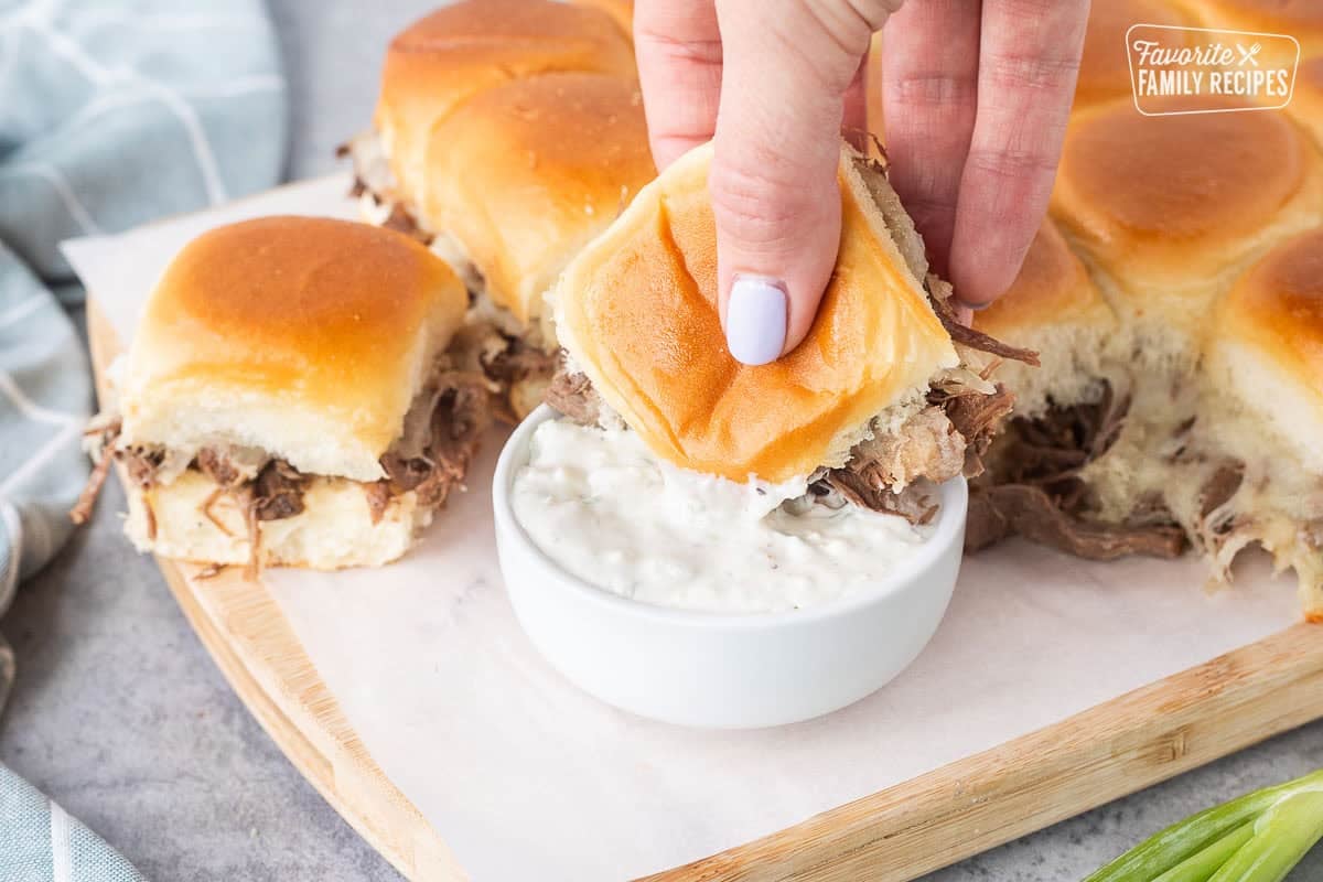 A roast beef slider dipped into creamy blue cheese horseradish sauce.