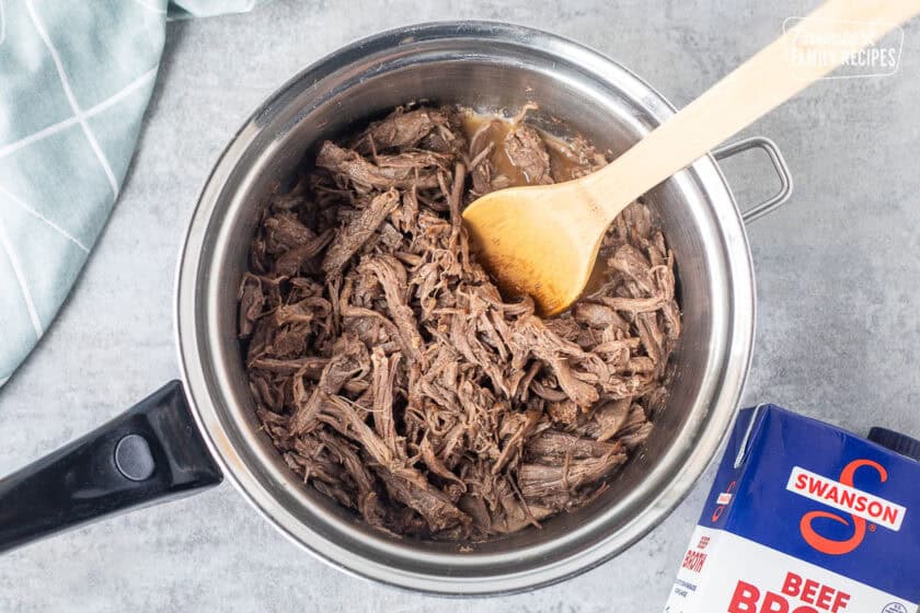 Saucepan with shredded beef and beef broth.