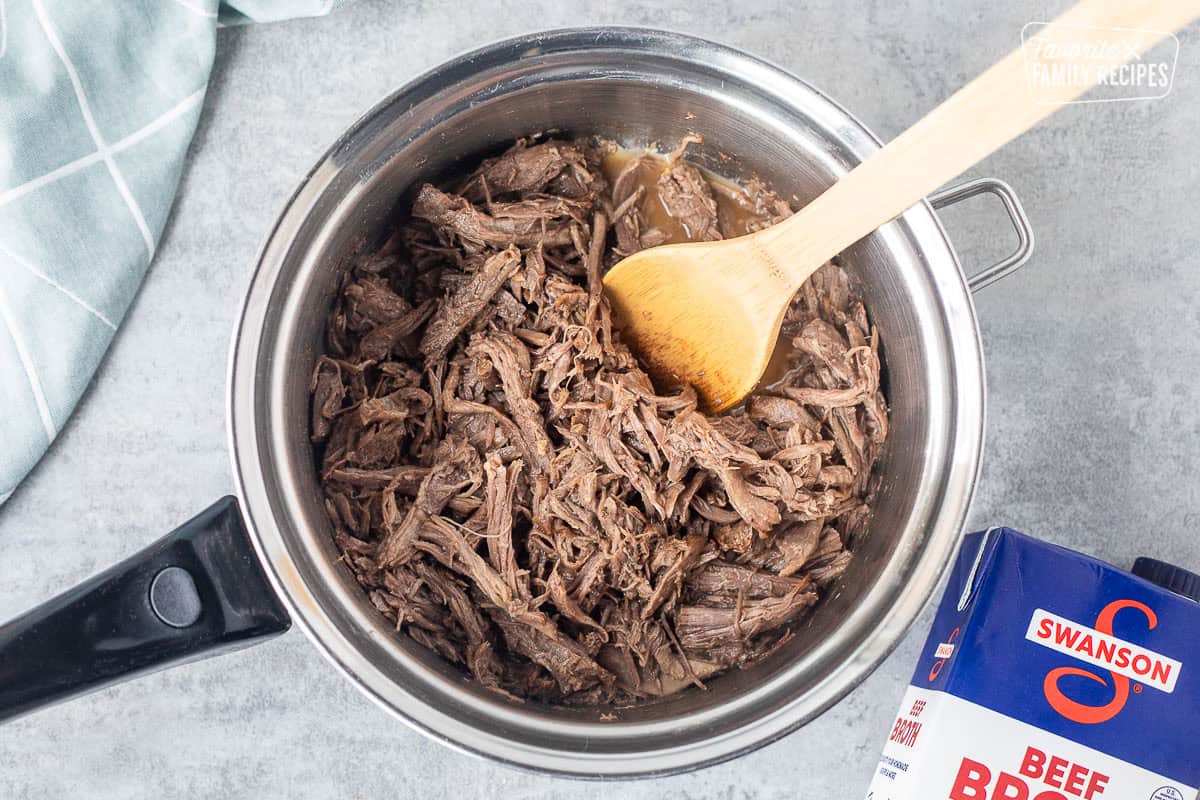 Saucepan with shredded beef and beef broth.