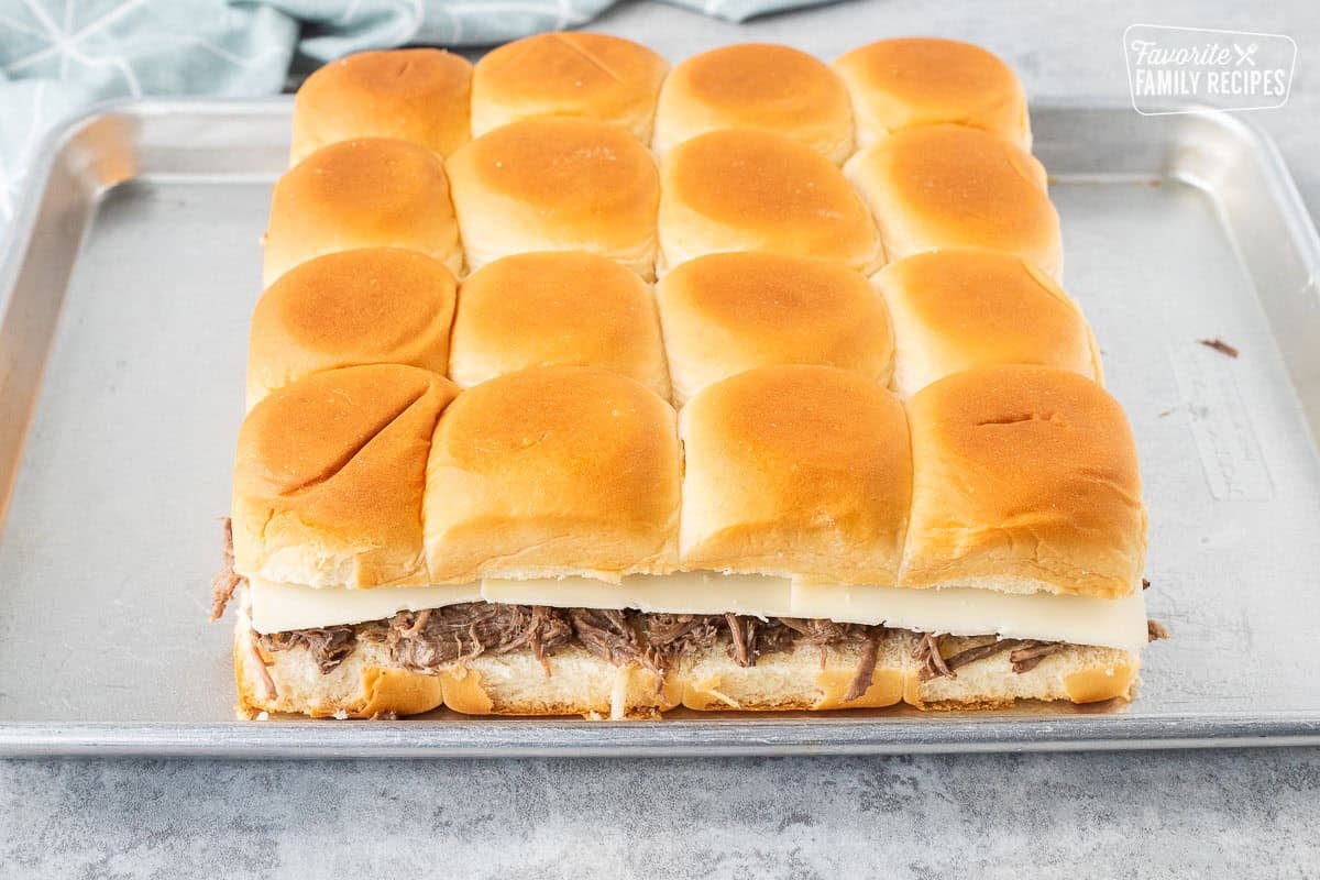 Unbaked sliders with roast beef and Swiss cheese.