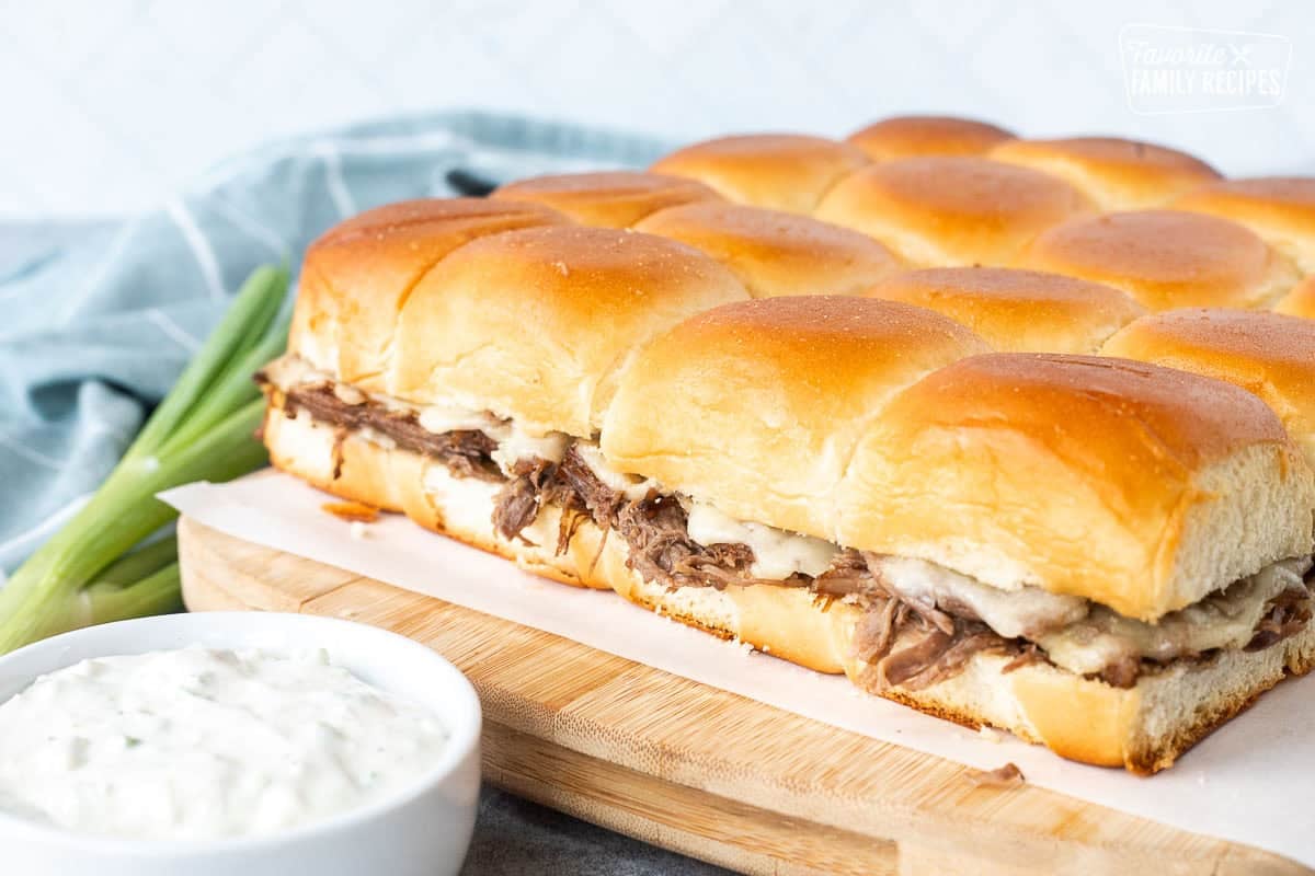 Roast beef sliders with Swiss cheese and blue cheese dressing on the side.