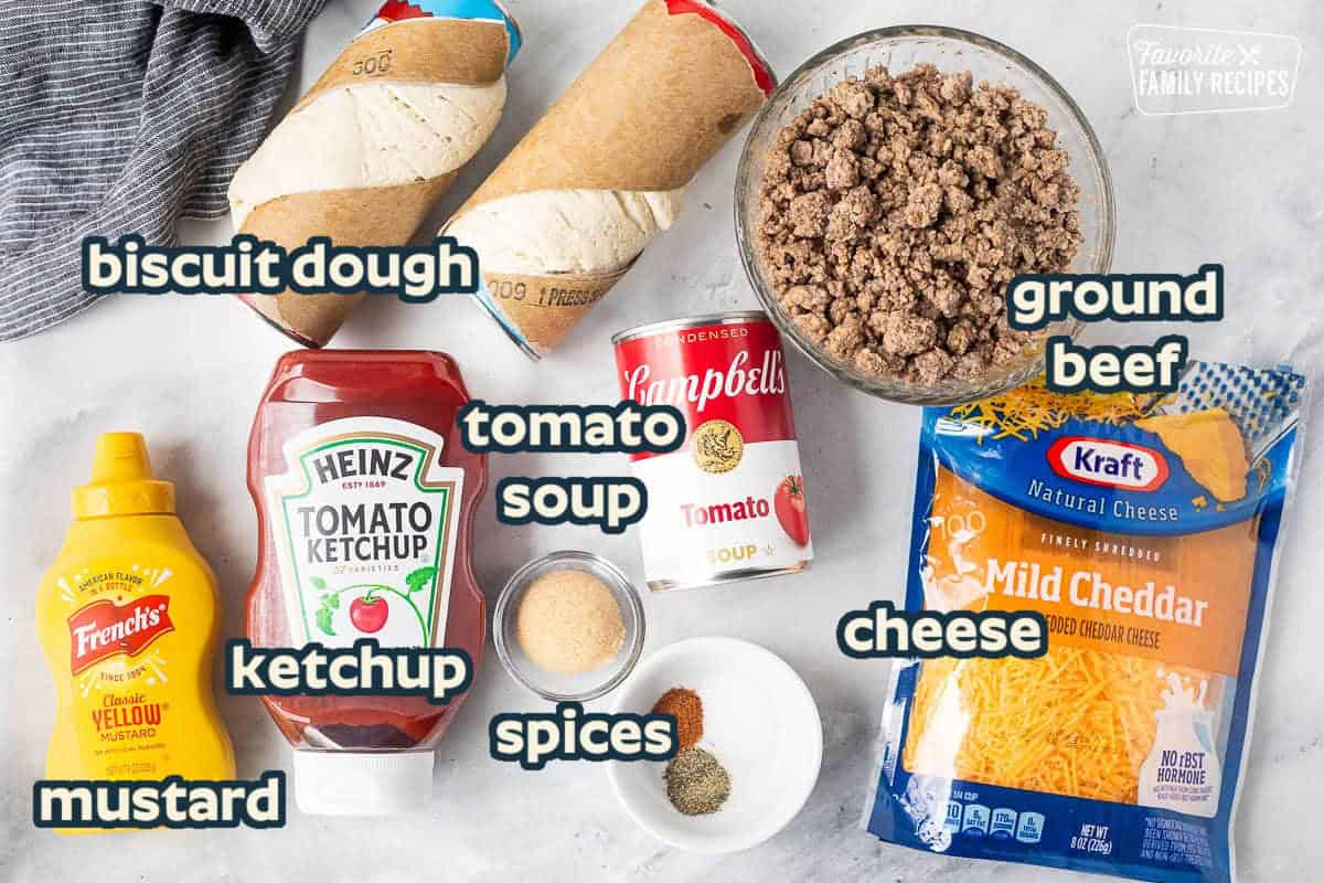 Ingredients to make Sloppy Joe Biscuits including ground beef, cheddar cheese, tomato soup, salt, pepper, cayenne pepper, brown sugar, ketchup, yellow mustard and refrigerated biscuits.