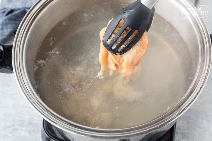 Placing marinated velvet chicken into pot of boiling water.
