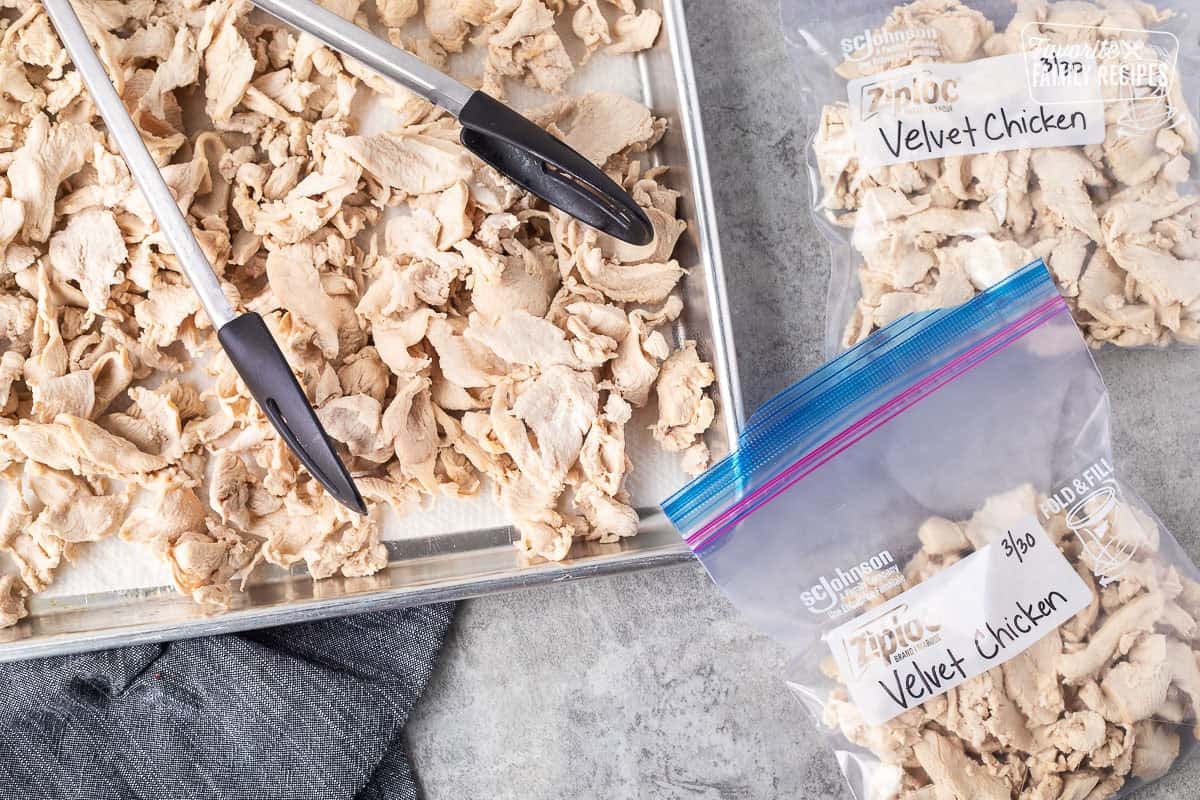 Moving velvet chicken from sheet pan to bags with tongs.