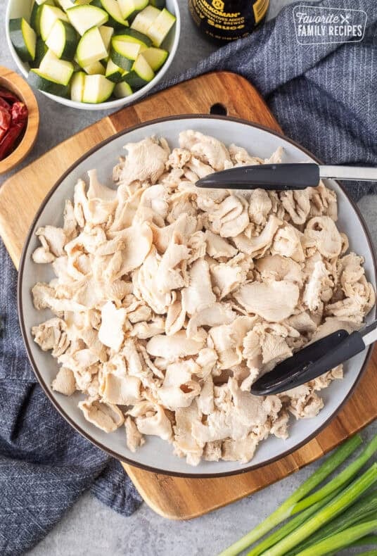 Plate of cooked velvet chicken with tongs.
