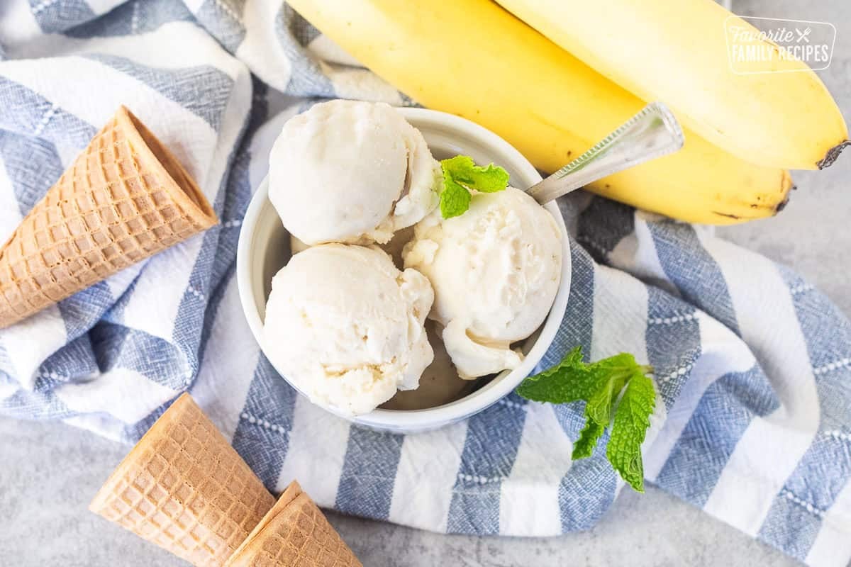 Three scoops of banana ice cream in a small dish and a spoon.