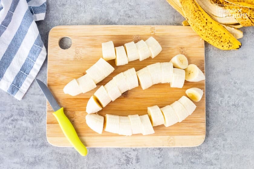 Cut bananas on a cutting board with a knife.