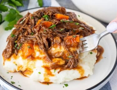 Plate of beef goulash over mashed potatoes.