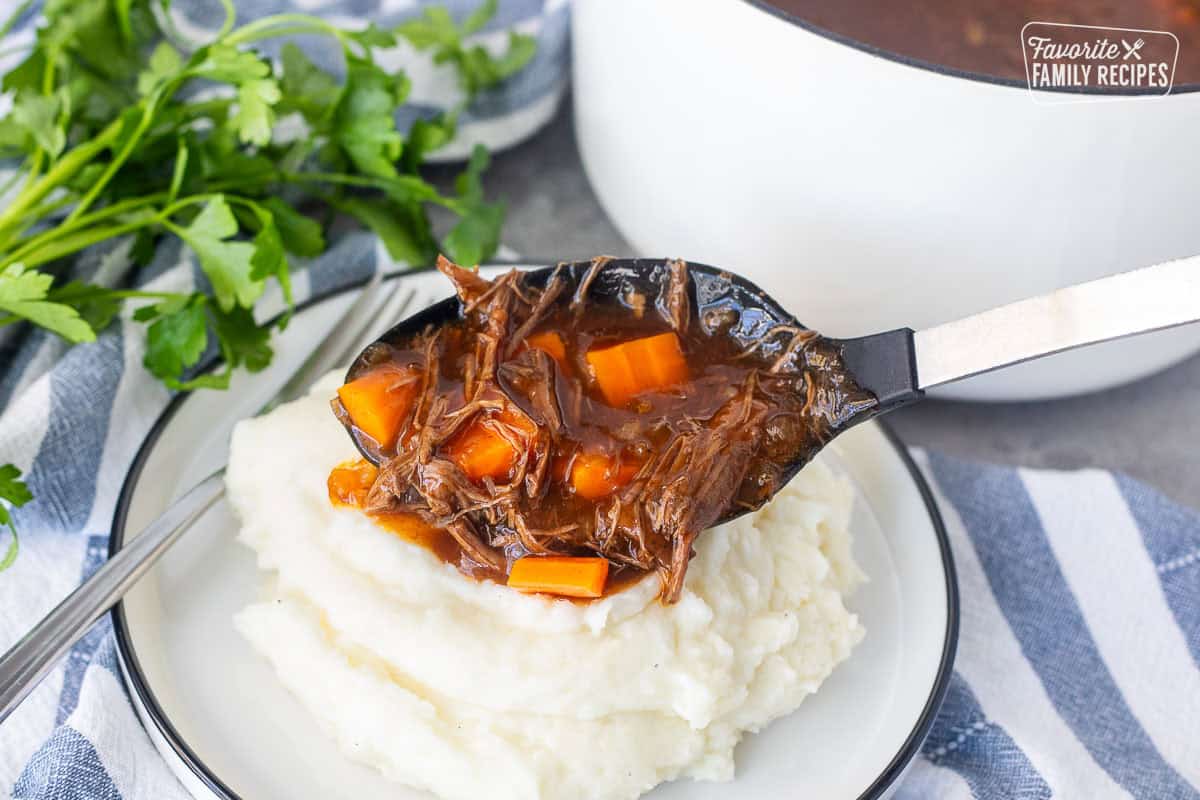 Pouring beef goulash onto mashed potatoes.