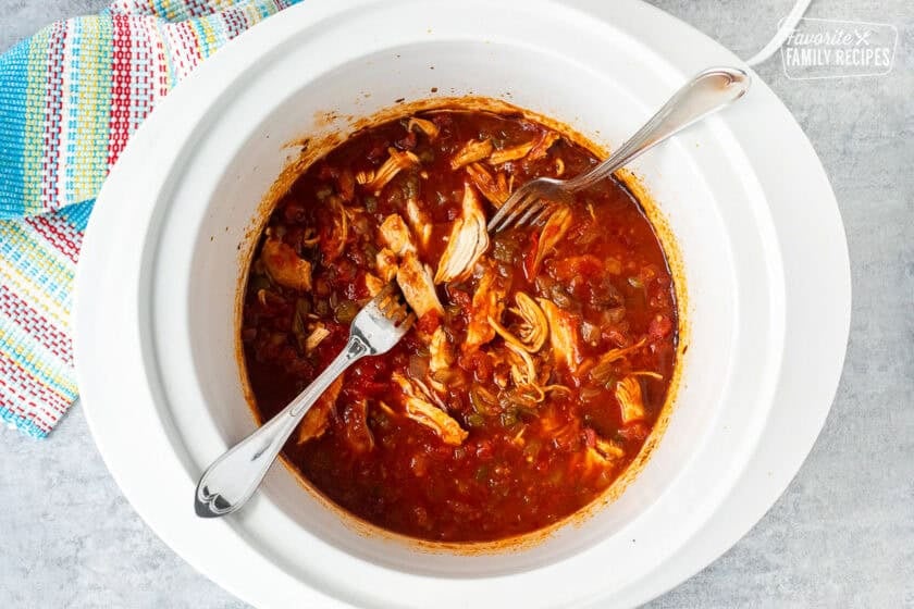 Crockpot with shredded chicken in tomato mixture.