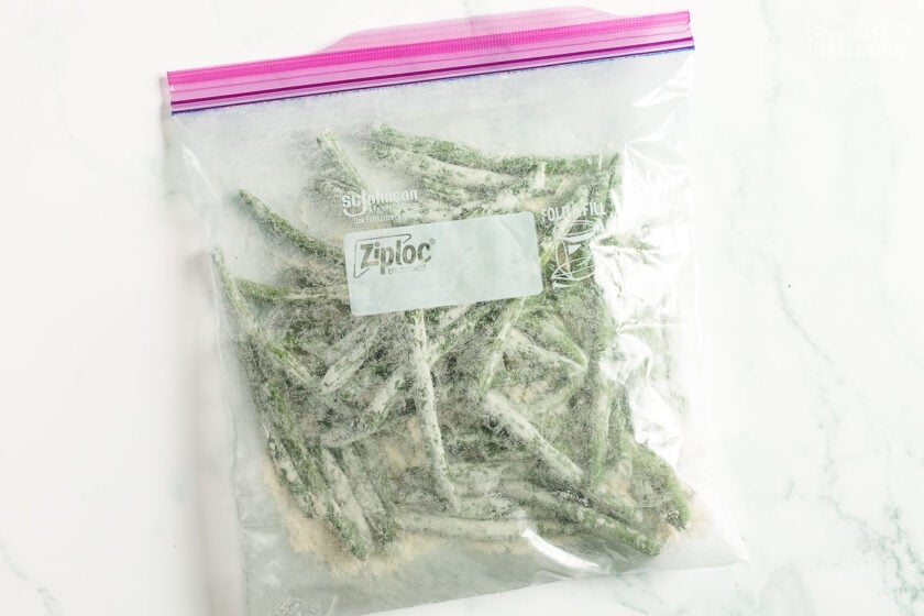 Green beans dredges in flour in a clear plastic Ziplock bag