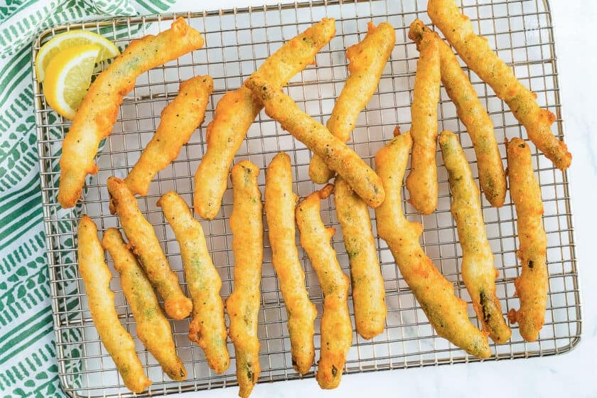 Rows of golden, crispy fried green beans on a wire cooling rack