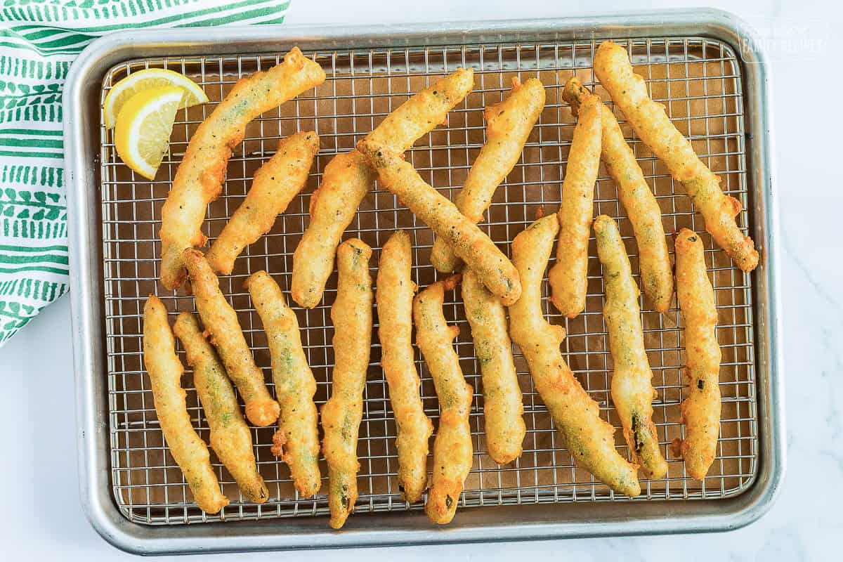 Rows of golden, crispy fried green beans on a wire cooling rack