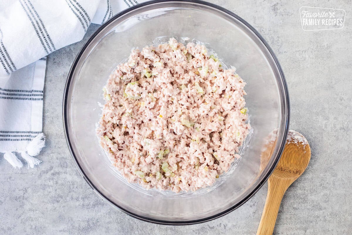 Mixing bowl with ham salad and wooden spoon on the side.