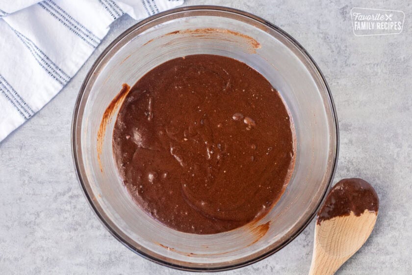 Glass mixing bowl with brownie wet ingredients mixed.