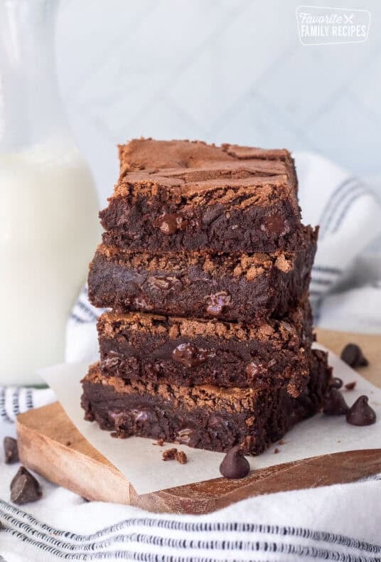 Stacked homemade brownies with a glass of milk.