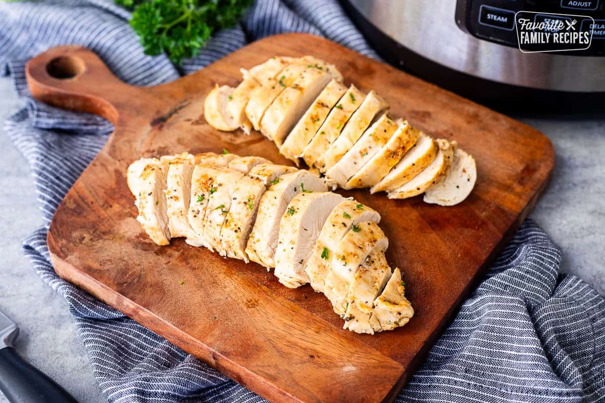 Cooked and sliced instant pot chicken breasts on a cutting board.